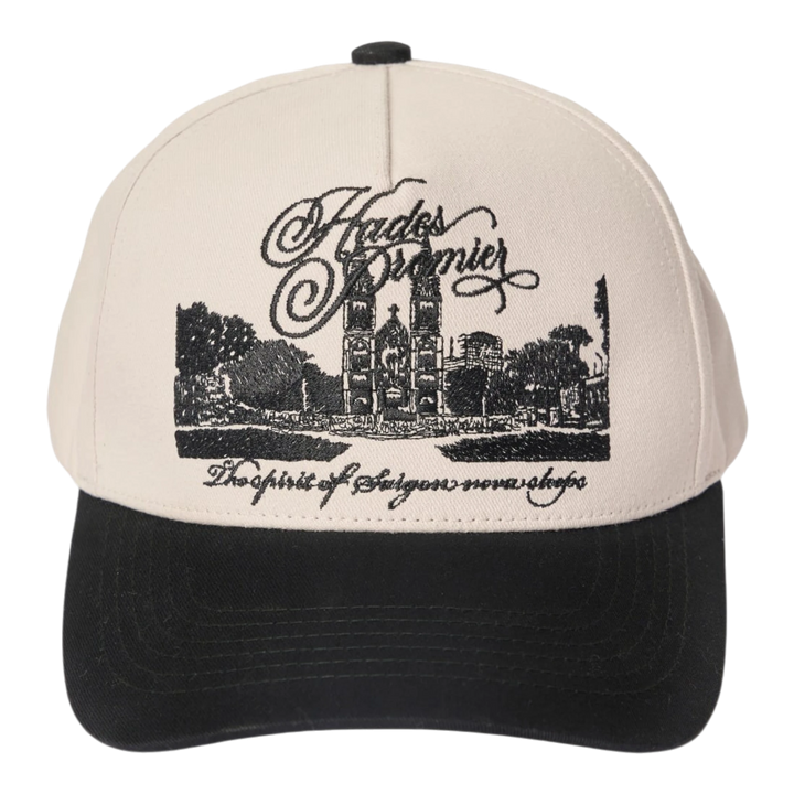 HADES Studio District 1 Cap: cream cotton cap with black brim, featuring embroidered Notre-Dame Cathedral Saigon and text.
