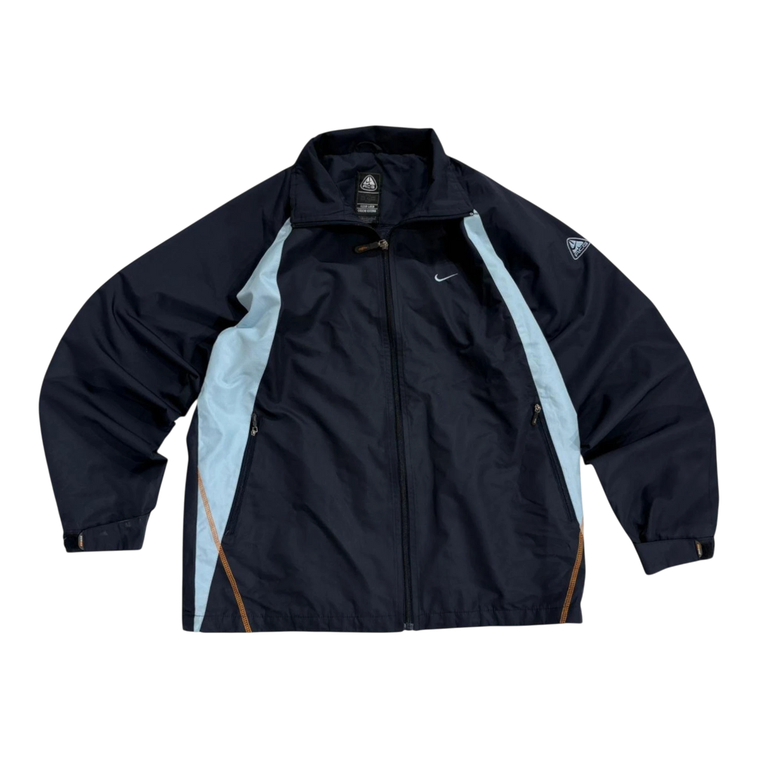 HypeSelection vintage Nike ACG windbreaker jacket in navy blue with light blue side panels and orange trim. Features a full zip and Nike logo.