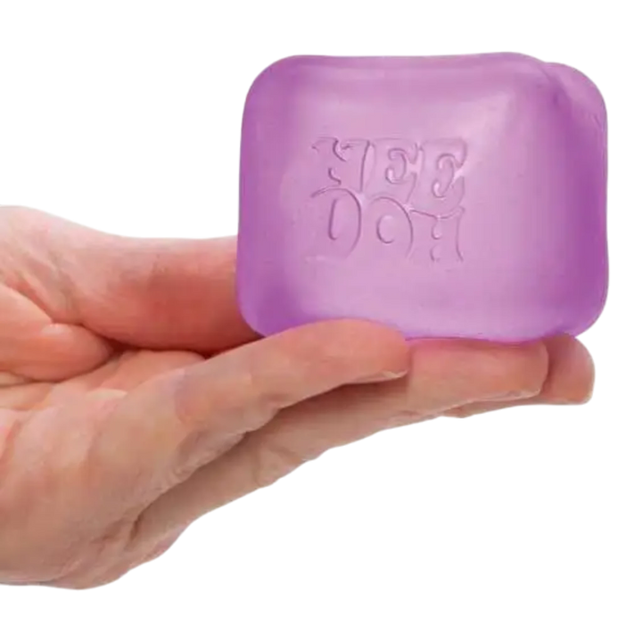 HypeSelection NeeDoh Nice Cube squishy fidget toy in translucent purple, held in a hand. Cube shape with slow-squish texture.
