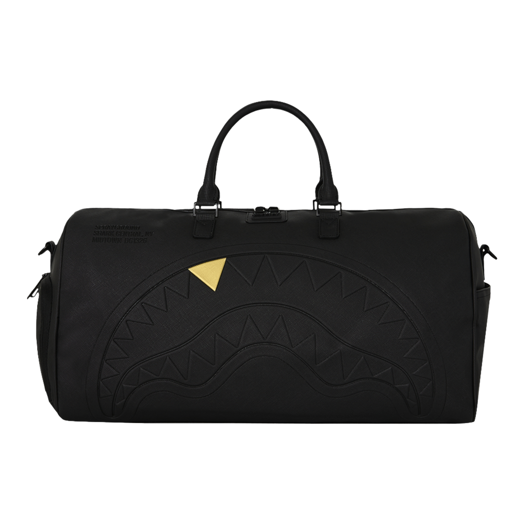 HypeSelection Sprayground black duffle bag featuring an embossed sharkmouth design with a metallic gold tooth detail.