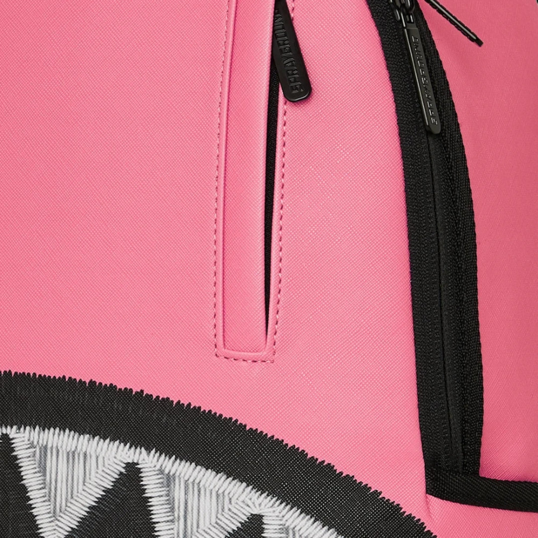 HypeSelection Sprayground Shark Central pink backpack with signature embroidered shark teeth detail and black zippers.