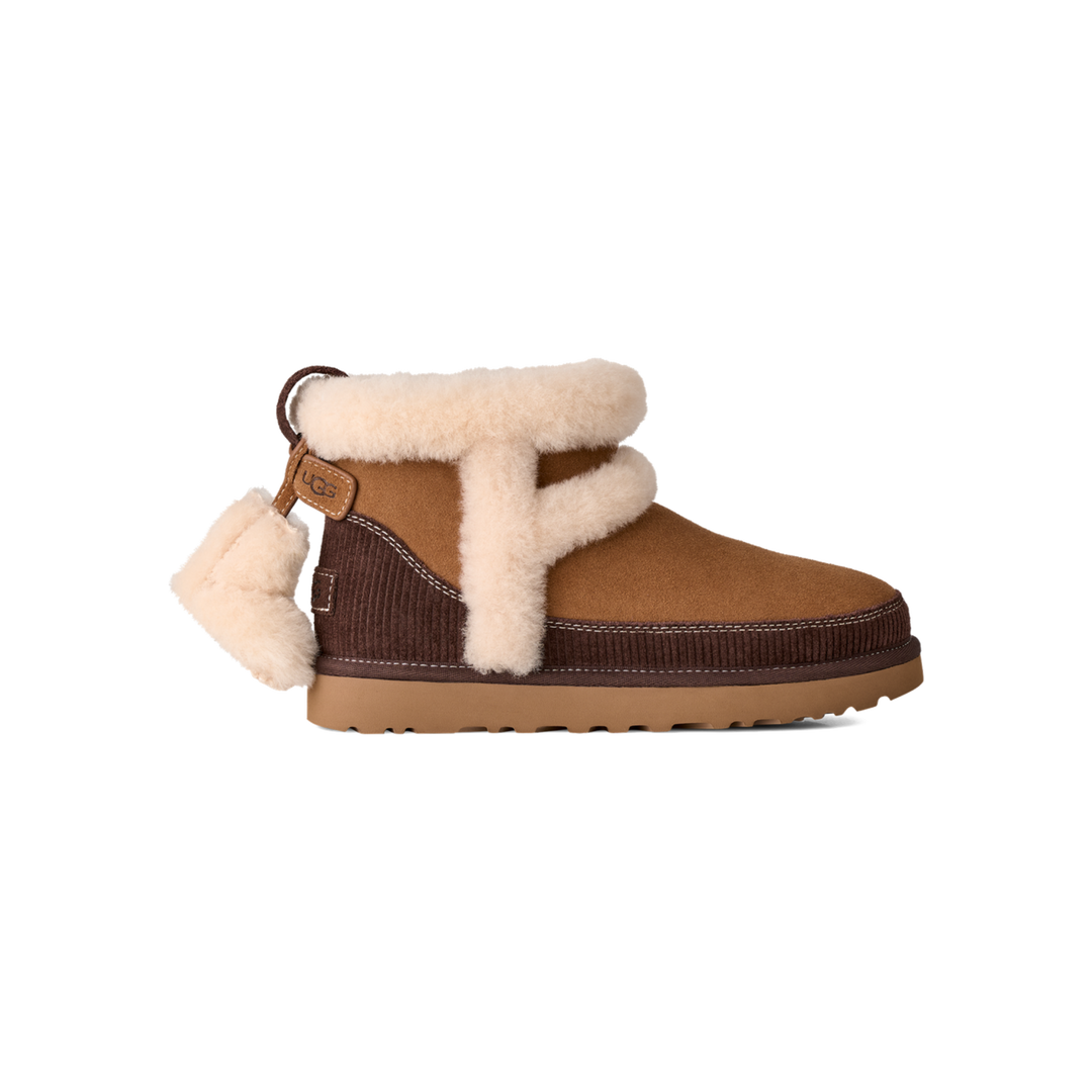 HypeSelection UGG Classic Mini Heritage boot in chestnut suede with plush sheepskin seams and a removable boot charm.