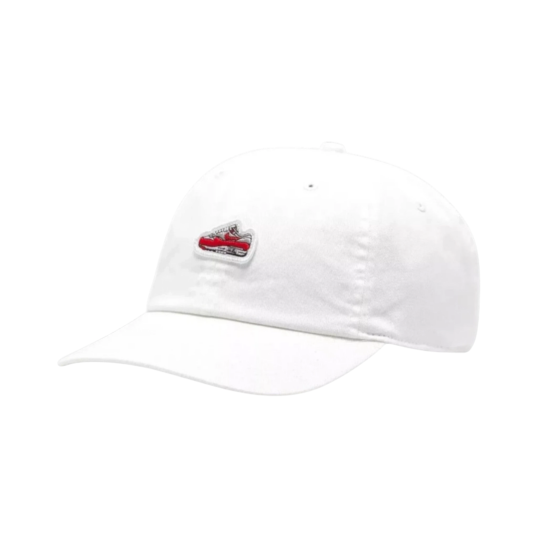 White cotton Nike Air Max 1 cap with embroidered red and white sneaker graphic on the front. Unstructured 6-panel design with pre-curved bill.